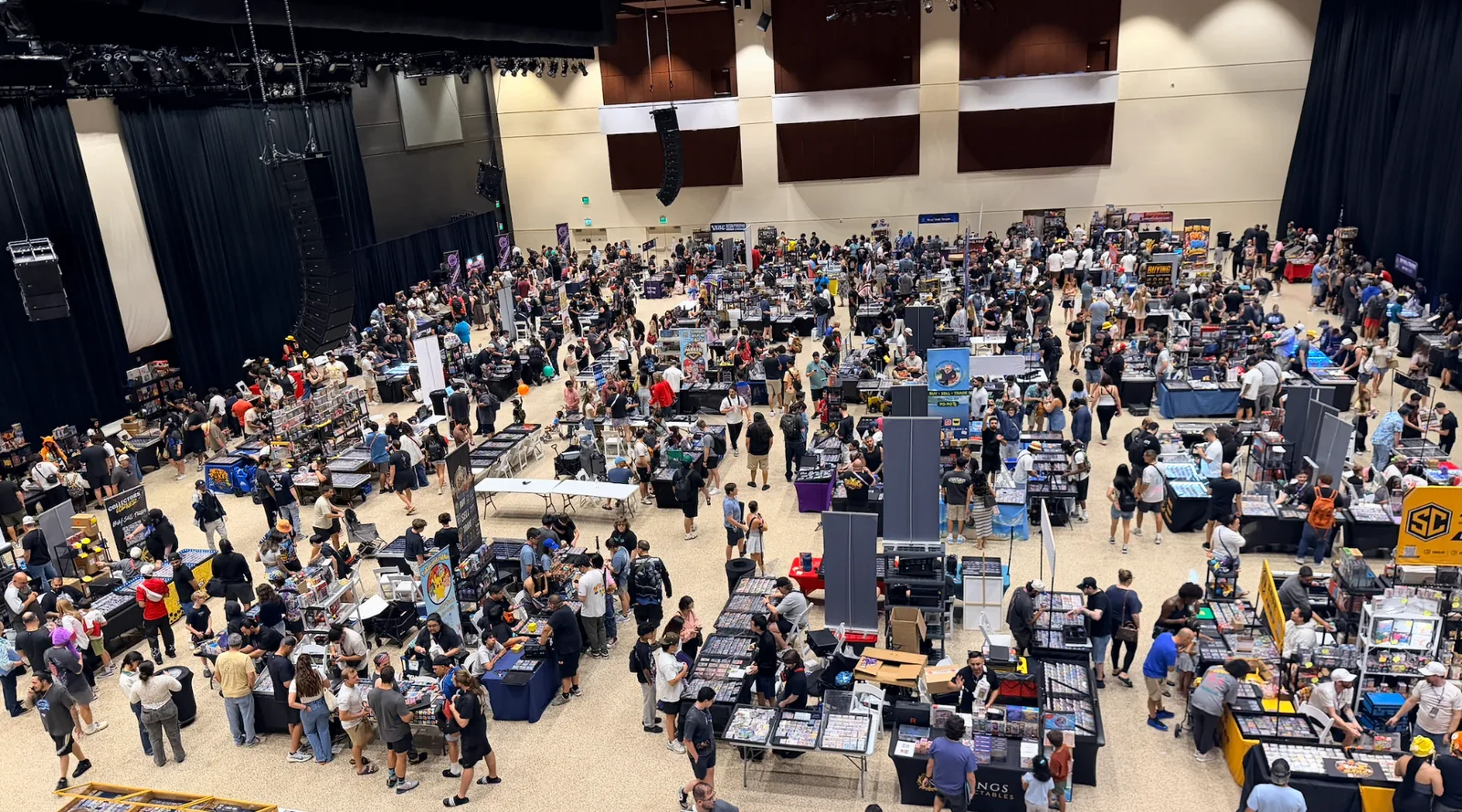 A crowded convention hall filled with vendor tables and collectors browsing and trading.